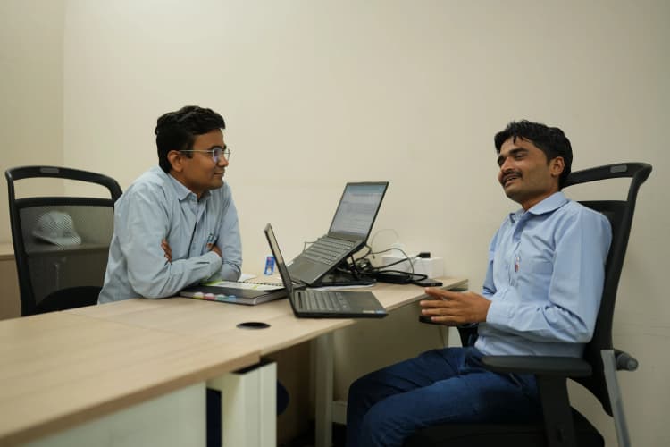 Aarti Industries employees in protective gear discussing operations inside industrial facility